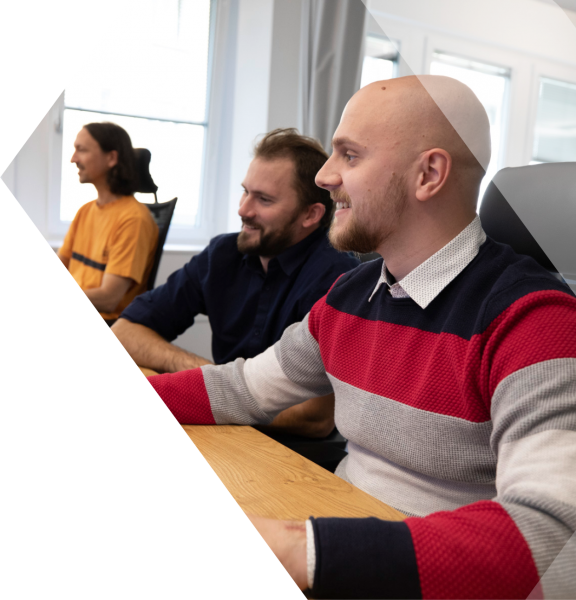 Zwei IT Xperten der HXS arbeiten an einem Computer und lächeln dabei