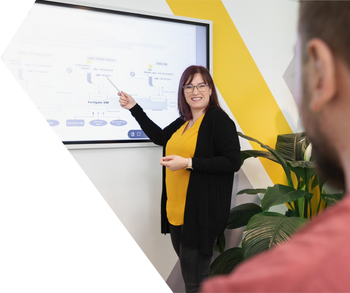 Eine Frau mit gelber Bluse erklärt an einem Smart Board etwas